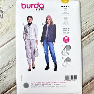 May include: A Burda Style sewing pattern packet featuring two women modeling jackets and pants. The packet includes the number 5799, size information, and the text "ALL PATTERNS WITH SEAM AND HEM ALLOWANCES". The background is a light wood grain.