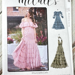 May include: McCall's sewing pattern M8087 featuring a pink off-the-shoulder maxi dress. The pattern includes multiple view options and simple instructions. The size range is A5 (6-8-10-12-14). The hashtag is #AuroraMcCalls.