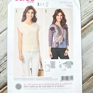 May include: A Burda Style sewing pattern packet, featuring two blouse designs. The packet is white with green accents and includes images of the finished garments, along with size information and instructions. The text on the packet includes "Burda Style" and "All Patterns with Seam and Hem Allowances."