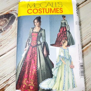 Peut inclure: Un paquet de patrons de couture McCall's Costumes avec des illustrations de robes historiques. Le paquet a un en-tête jaune avec le nom de la marque et des images des vêtements finis en vert, rouge et bleu.