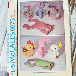 May include: Vintage McCall's 5973 sewing pattern envelope featuring fabric animal designs. The envelope displays a variety of stuffed animals, including bunnies, a frog, a chick, and a duck. The text "SET OF ANIMALS IN TWO SIZES" is visible.