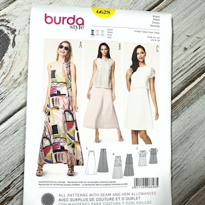 May include: A Burda Style sewing pattern packet, featuring three dress designs. The packet displays images of the finished dresses, along with diagrams and sizing information. The packet is white with the number 6628 in yellow.