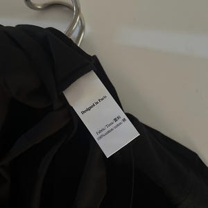 May include: A white tag with black text that reads "Designed in Paris" and "Fabric/Tissu/面料 100%cotton/coton/棉".