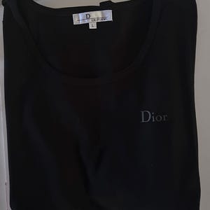 May include: Black sleeveless shirt with a white tag that says "D UNIFORMS L" and a small grey "Dior" logo on the front.