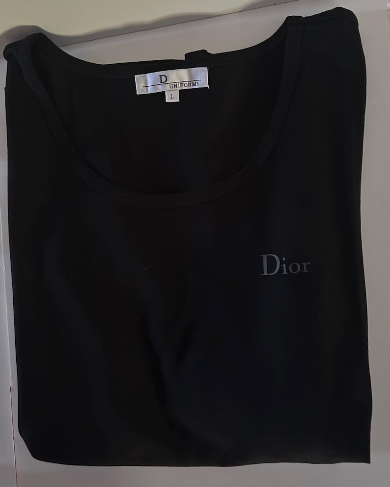 May include: Black sleeveless shirt with a white tag that says "D UNIFORMS L" and a small grey "Dior" logo on the front.