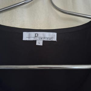 May include: A black uniform shirt with a white tag that reads "D UNIFORMS" and "L" for size.