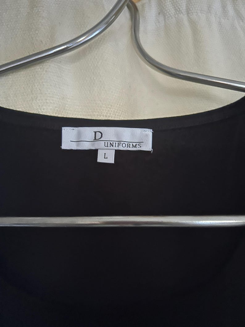 May include: A black uniform shirt with a white tag that reads "D UNIFORMS" and "L" for size.