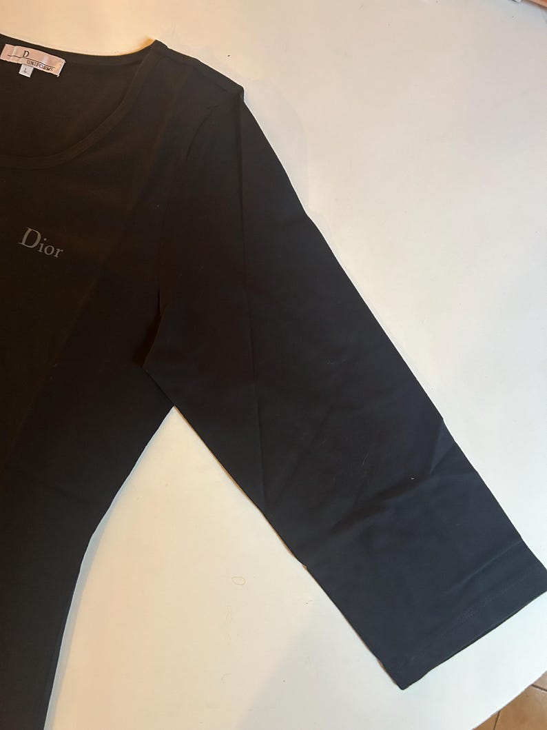 May include: Black long-sleeved t-shirt with a white "Dior" logo on the front.