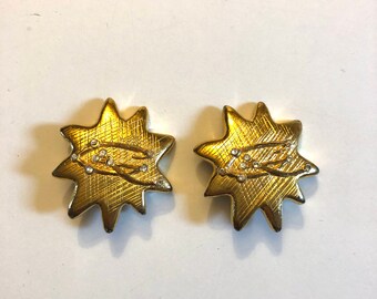 May include: A pair of gold tone star-shaped earrings with clear rhinestone accents.