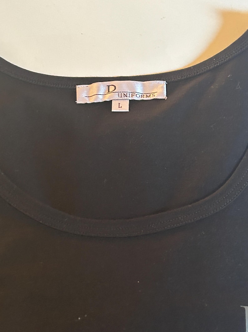 May include: Black sleeveless shirt with a white tag that reads "D UNIFORMS" and a size "L" label.