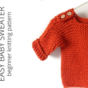 May include: A bright orange knitted baby sweater with wooden buttons. The sweater has a simple design and is perfect for a beginner knitter.