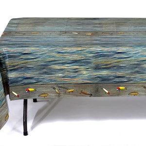 May include: A blue and brown plastic tablecloth with a fishing lure design. The tablecloth features a wood plank pattern with a wavy water design and a row of fishing lures along the bottom.