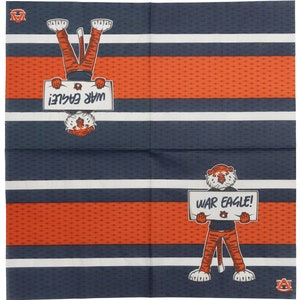 May include: A set of four blue and white striped napkins with an orange pattern. Each napkin features a cartoon tiger holding a sign that says "War Eagle!" The tiger is wearing blue jeans and a white shirt with an orange logo. The napkins are perfect for a game day party or tailgating.