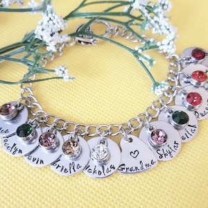 May include: A silver charm bracelet with a heart charm that says "Grandma" and other charms with names like "Skylar", "Nicholas", "Briella", "Kevin", and "Jocelyn".