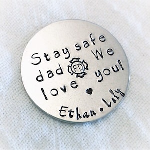 May include: A silver round disc with the text "Stay safe dad We love you!" and a firefighter's badge with the letters "FD" inside. The text "Ethan. Lily" is also on the disc.