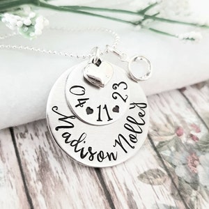 May include: Silver necklace with a round pendant that says "Madison Noelle" and "04.11.23" with a small heart charm.