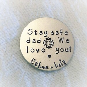May include: Silver round keychain with the text "Stay safe dad We love you!" and a small heart. The text "Ethan & Lily" is below the heart. A fire department logo is included in the text.