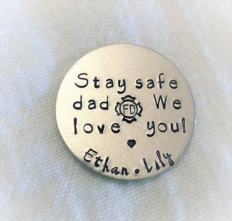 May include: Silver round keychain with the text "Stay safe dad We love you!" and a small heart. The text "Ethan & Lily" is below the heart. A fire department logo is included in the text.
