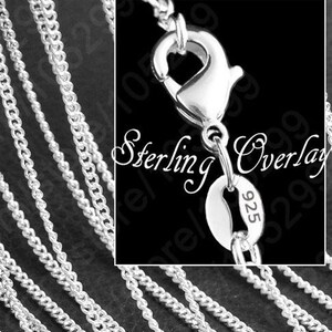 May include: A close-up of a silver chain necklace with a lobster clasp and a tag that reads "Sterling Overlay 925".