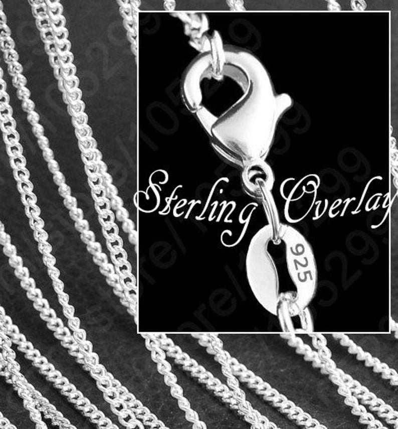 May include: A close-up of a silver chain necklace with a lobster clasp and a tag that reads "Sterling Overlay 925".