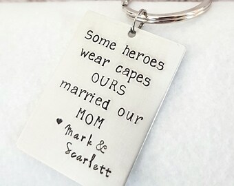 May include: Silver keychain with the text "Some heroes wear capes OURS married our MOM Mark & Scarlett"