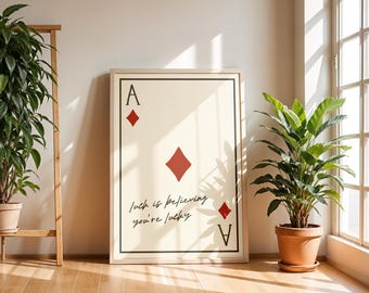 May include: A framed print with a white background and a red diamond playing card with the letter A and the text "Luck is believing you're lucky".