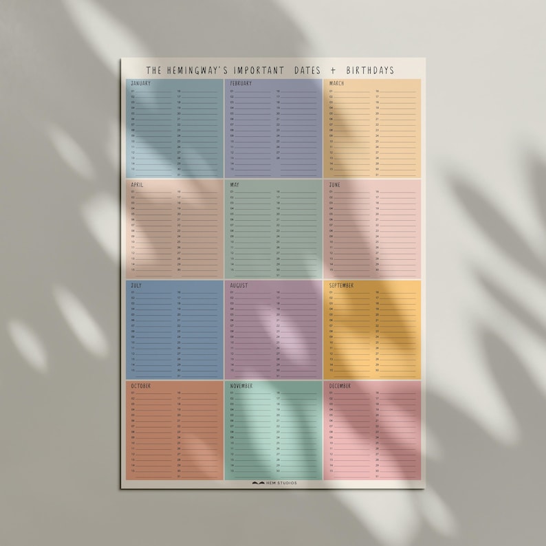 May include: A colorful wall calendar titled "THE HEMINGWAY'S IMPORTANT DATES + BIRTHDAYS." The calendar features twelve months, each in a different pastel color, with dates listed in columns. The design is minimalist and modern, suitable for home or office.