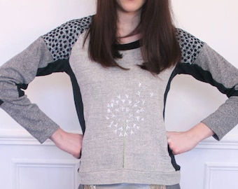 Grey jumper with contrasting cut-outs. Hand-embroidered dandelion flower motif