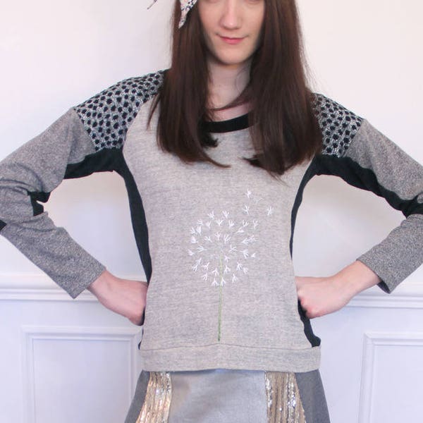 Grey jumper with contrasting cut-outs. Hand-embroidered dandelion flower motif