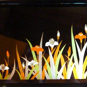 Könnte beinhalten: Schwarzes Lacktablett mit goldener Einfassung und einem Blumendesign mit weißen und orangefarbenen Blumen und grünen Blättern.