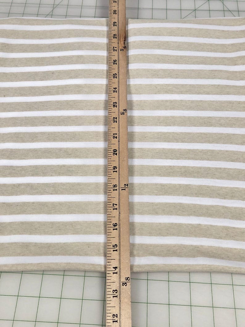May include: Tan and white striped fabric with a wooden ruler measuring 30 inches. The fabric has horizontal stripes, with alternating tan and white bands. The ruler is positioned vertically, showing inch measurements.