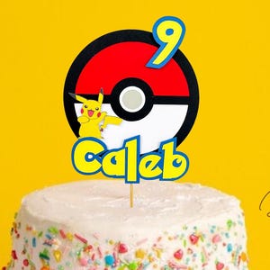 May include: A white cake with colorful sprinkles topped with a Pokemon themed cake topper. The topper features a red and white Pokeball with Pikachu and the number 9. The name Caleb is written below the Pokeball. The cake is on a white cake stand.