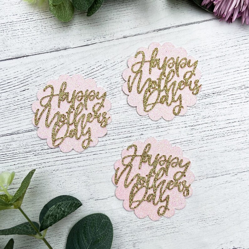 Puede incluir: Tres c&iacute;rculos de papel rosa y dorado con purpurina con el texto "Happy Mother's Day" en cada uno.