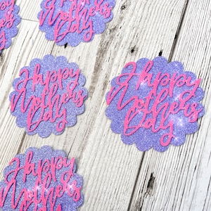 Puede incluir: Recortes de papel con purpurina morada con bordes festoneados y el texto "Happy Mother's Day" en letras de purpurina rosa.
