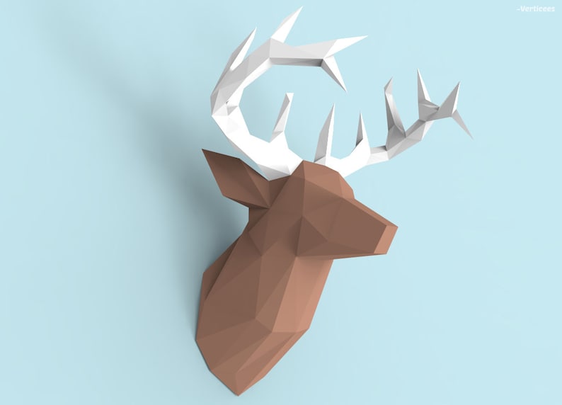 May include: A brown paper deer head with white paper antlers. The deer head is made of folded paper and has a geometric design.