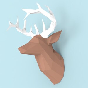 May include: A brown paper deer head with white paper antlers. The deer head is a 3D origami sculpture.