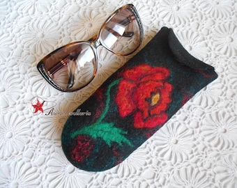 May include: A black felt eyeglass case with a red poppy flower design. The case is lying on a white crocheted surface next to a pair of brown tortoise shell sunglasses.