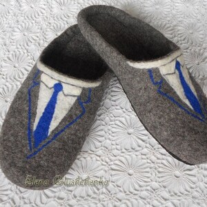 May include: Gray felt slippers with a blue and white embroidered design of a suit and tie.