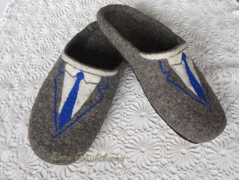 May include: Gray felt slippers with a blue and white embroidered design of a suit and tie.