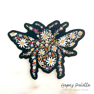 May include: Black and white sticker of a bee made of flowers. The bee is surrounded by white daisies and other colorful flowers. The sticker has the text "Hope's Palette Art by Daisy Ring" at the bottom.
