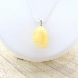 Peut inclure: Un pendentif en citrine jaune sur une chaîne en argent. Le pendentif est de forme ovale lisse.