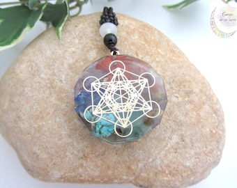 May include: A round, multi-colored crystal pendant with a gold geometric design inside. The pendant is on a black cord with a white bead.