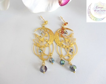 May include: Gold earrings with a crescent moon design and crystal accents. The earrings have dangling crystal beads.