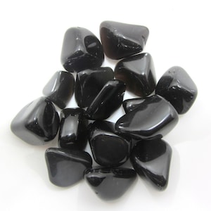 Peut inclure: Une collection de pierres d'obsidienne noire roulées. Les pierres sont lisses et polies, avec une finition brillante.