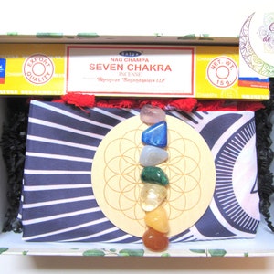 Peut inclure: Une boîte-cadeau contenant un tissu rayé noir et blanc, un cercle en bois avec un motif géométrique et sept pierres colorées, ainsi qu'une boîte de bâtonnets d'encens étiquetés "Satya Nag Champa Seven Chakra Incense".