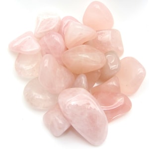 Peut inclure: Une collection de pierres de quartz rose roulées. Les pierres sont de couleur rose pâle et ont une finition lisse et polie.