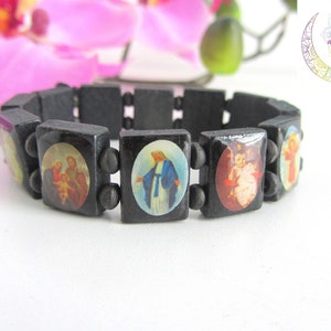 May include: Black wooden bracelet with round images of religious figures. The bracelet has a total of 9 beads, with 5 of the beads featuring images of religious figures.