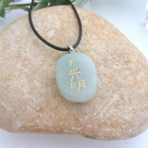 May include: A green stone pendant necklace with a black cord. The stone has gold lettering that reads "大吉日".