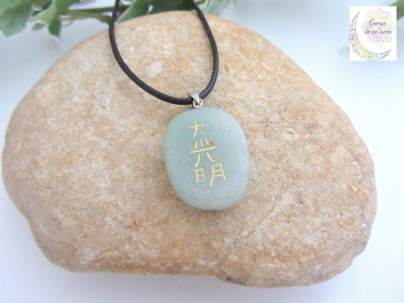 May include: A green stone pendant necklace with a black cord. The stone has gold lettering that reads "大吉日".
