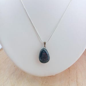 K&ouml;nnte beinhalten: Eine silberne Kettenkette mit einem Anh&auml;nger aus dunkelgr&uuml;nem Edelstein. Der Anh&auml;nger hat eine glatte, ovale Form.